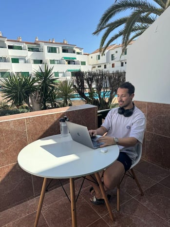man sitting on terrace working on laptop
