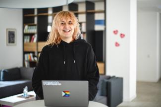 Blonde person smiling behind a laptop