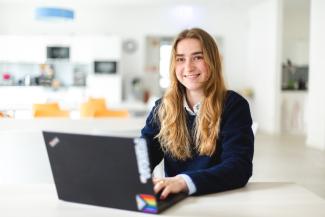 young woman with long blonde hair sitting at a laptop